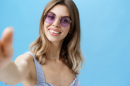 Charming woman with cute gapped teeth in sunglasses relaxing on vacation taking beautiful shots...