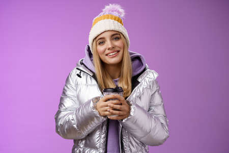 Tender relaxed cheerful smiling blond girl look pleased relieved drinking hot coffee cacao enjoying...