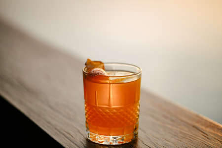 Glass of orange cocktail decorated with orange garnish at bar counter backgroundの写真素材