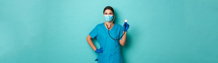Covid-19, pandemic and medicine concept. Beautiful female doctor in medical mask, gloves and scrubs,...