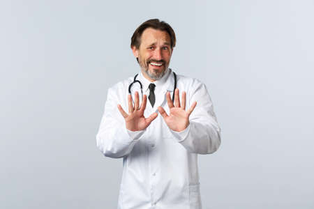Covid-19, coronavirus outbreak, healthcare workers and pandemic concept. Displeased and bothered doctor rejecting something awful, shaking hands in refusal or denial, look alarmedの写真素材