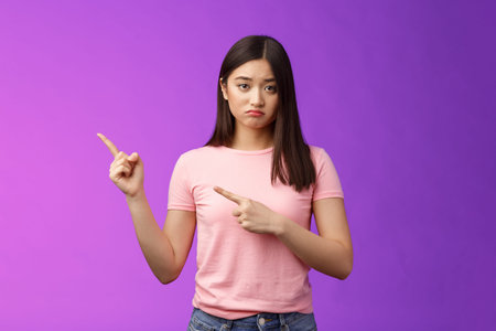 Moody upset whining girlfriend unhappy pointing left, sulking look miserable and distressed, express...
