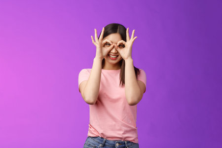 Cheerful friendly carefree asian woman having fun fool around, show okay ok signs on eyes make...