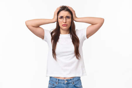 Waist-up portrait of troubled female student have big problem, grab head frowning and grimacing facing complex situation, dont know what do, standing desperate and embarrassedの写真素材