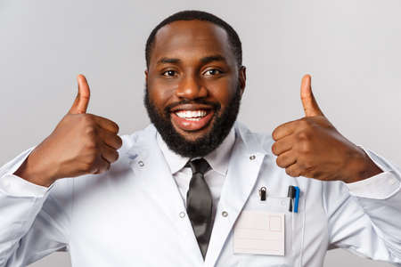 Healthcare, medicine and hospital treatment concept. Close-up portrait of satisfied, happy african-american doctor, physician assure patient do check-up this clinic, best hospital, recommendingの写真素材