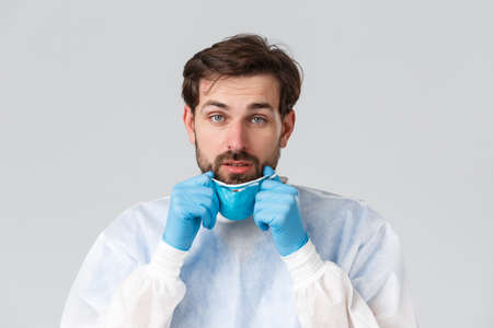Covid-19, pandemic, healthcare workers fighting virus. Tired and exhausted doctor take-off medical respirator, gloves, feeling fatigue for working night shift in hospital with coronavirus patientsの写真素材