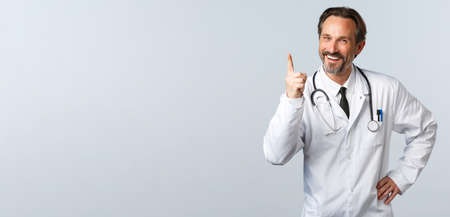 Covid-19, coronavirus outbreak, healthcare workers and pandemic concept. Well played, nice work. Cheerful male doctor in white coat shaking finger and laughing as scolding someoneの写真素材