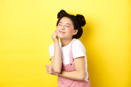 Beautiful happy woman with bright pink makeup, close eyes and touch soft skin, smiling excited,...