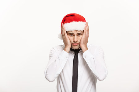 Christmas Concept - Handsome Business man wear santa hat posing with stressful facial expression on white isolated background.の写真素材