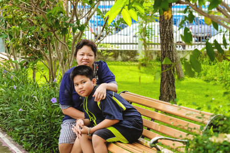 Happy asian woman, mother sitting with her son and sitting in the park