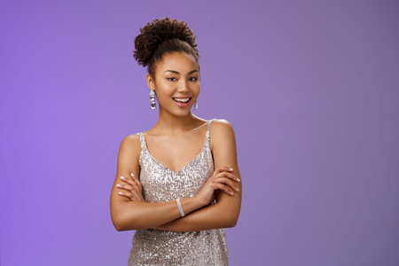 Stylish lucky happy attractive african-american female in glittering silver night-dress cross arms...