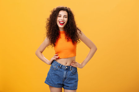 Stylish confident and awesome woman ready lit party standing in trendy cropped top and denim shorts...