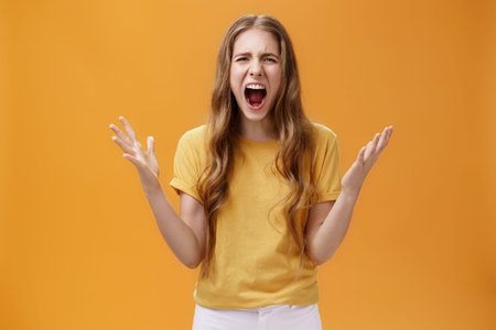 Studio shot of young woman during argument losing temper standing pressured and pissed yelling out...
