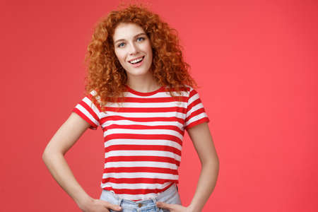 How hanging. Friendly carefree redhead curly-haired relaxed outgoing woman speaking casually entertained happy mood hold hands jeans pockets tilt head intrigued, curiously look cameraの写真素材