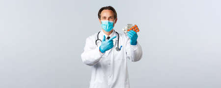 ealthcare workers and vaccination concept. Pharmacist recommend medication. Doctor in medical mask and gloves pointing at pills, prescribe medicineの写真素材