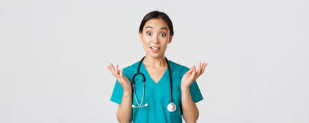 Healthcare workers, preventing virus, quarantine campaign concept. Close-up of surprised and amused, happy asian female nurse, physician hear great news, raise hands amazed and look cameraの写真素材