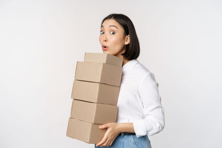 Portrait of young asian woman holding boxes, carry delivery goods. Korean female entrepreneur...