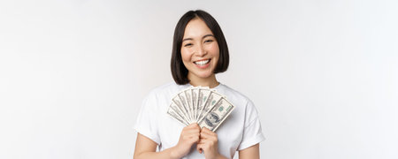 Portrait of smiling asian woman holding dollars money, concept of microcredit, finance and cash,...