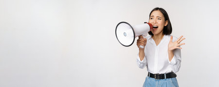 Image of young woman, korean activist, recruiter screaming in megaphone, searching, shouting at loudspeaker, standing over white backgroundの写真素材