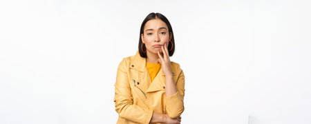 Image of stylish japanese girl looking with unamused, tired and upset face expression, standing in...