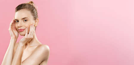 Beauty Spa Concept - Caucasian Woman with perfect face skin Portrait. Beautiful Brunette Spa Girl showing empty copy space. Isolated on pink studio background. Proposing a product.の写真素材