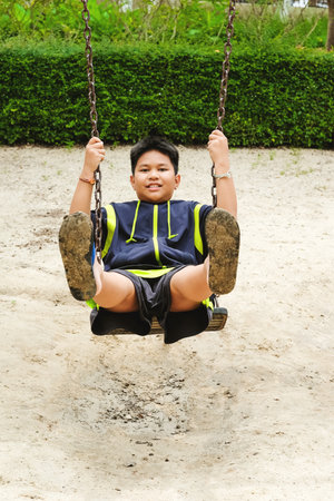 Happy asian sport boy play on swing playground in Garden.の写真素材