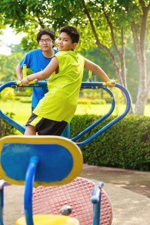Child playing on outdoor playground. Kids play on school or kindergarten yard. Active kid on colorful swing. Healthy summer activity for children. Little boy swinging in tropical gardenの写真素材