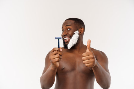 Young Afro American Man Shaving in Bathroom. Personal Morning Routine. Hygiene at Morning Concept.の写真素材