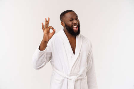 Young African man in bathrobe prepare for skin care showing ok finger sign. Human emotions conceptの写真素材