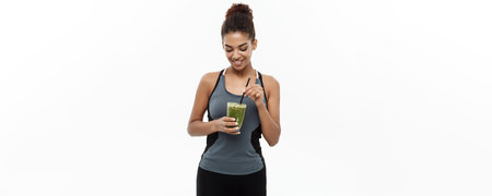 Healthy and Fitness concept - Beautiful American African lady in fitness clothing drinking healthy...