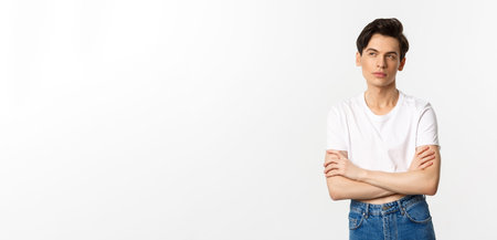Thoughtful gay man in crop top looking at upper left corner, thinking with arms crossed on chest,...