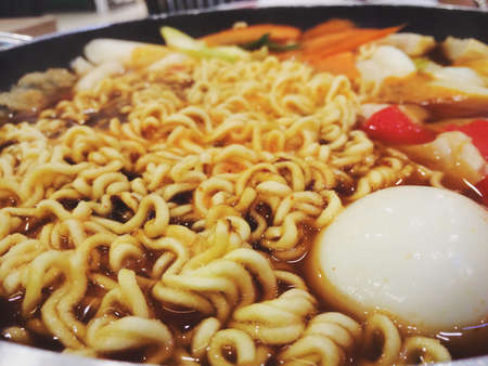 Close up image of Korean spicy instant noodle, Ramyun, with egg yolk inside a korean noodle pot.の写真素材