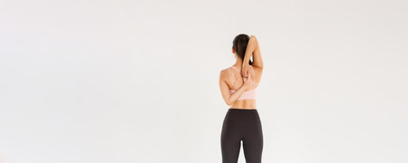 Full length rear view of active and slim brunette asian fitness girl, female athlete warm-up before...