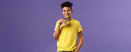 Portrait of good-looking young male student with dreads, tattoos, casually drinking coffee from take-away cup, visit favorite cafe, smiling cheerful, enjoying perfect warm sunny dayの写真素材