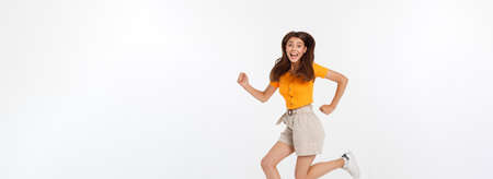 Portrait of a joyful woman jumping in the studio with happy feeling, isolated on white background, 20-28 year old.の写真素材