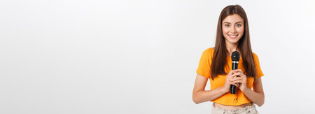 Young pretty woman happy and motivated, singing a song with a microphone, presenting an event or...