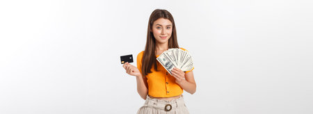 Photo of happy young woman standing isolated over grey background. Looking aside holding money and...