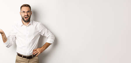 Frustrated office worker complaining, gesturing and looking disappointed, standing over white backgroundの写真素材