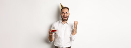 Holidays and celebration. Birthday guy making wish on bday cake and rejoicing, making fist pump sign...