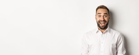 Close-up of caucasian bearded man looking excited, standing amazed against white background