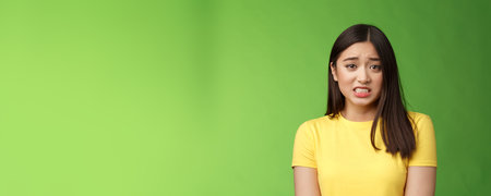 Anxious worried cute asian girl brunette clench teeth frowning shaking from fear look guilty afraid,...