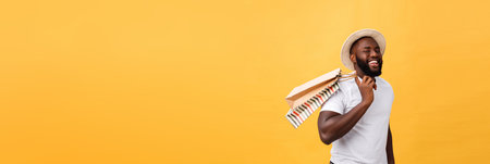 Happy african american man holding shopping bags on yellow background. Holidays conceptの写真素材