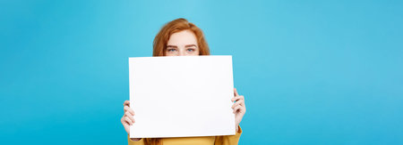 Close up Portrait young beautiful attractive redhair girl smiling showing blank sign. Blue Pastel...