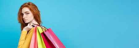 Shopping Concept - Close up Portrait young beautiful attractive redhair girl looking at camera. Blue Pastel Background. Copy space.の写真素材