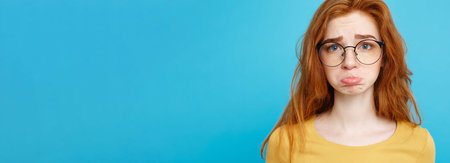 Headshot Portrait of happy ginger red hair girl with freckles smiling looking at camera. Pastel blue background. Copy Space.の写真素材