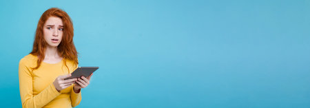 Close up Portrait young beautiful attractive tender ginger redhair girl happy smiling on digital table with wining something. Blue Pastel Background. Copy spaceの写真素材