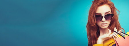Shopping Concept - Close up Portrait young beautiful attractive redhair girl smiling looking at camera with shopping bag. Blue Pastel Background. Copy spaceの写真素材