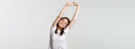 Portrait of relaxed carefree brunette girl stretching with satisfied smileの写真素材