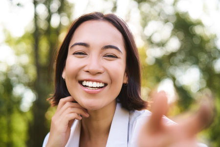 Genuine people. Portrait of asian woman laughing and smiling, walking in park, feeling joy and positivityの写真素材