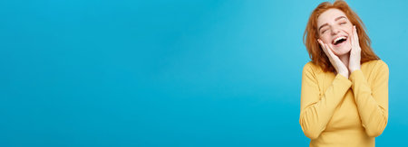 Lifestyle concept - Portrait of cheerful happy ginger red hair girl with joyful and exciting smiling to camera. Isolated on Blue Pastel Background. Copy space.の写真素材